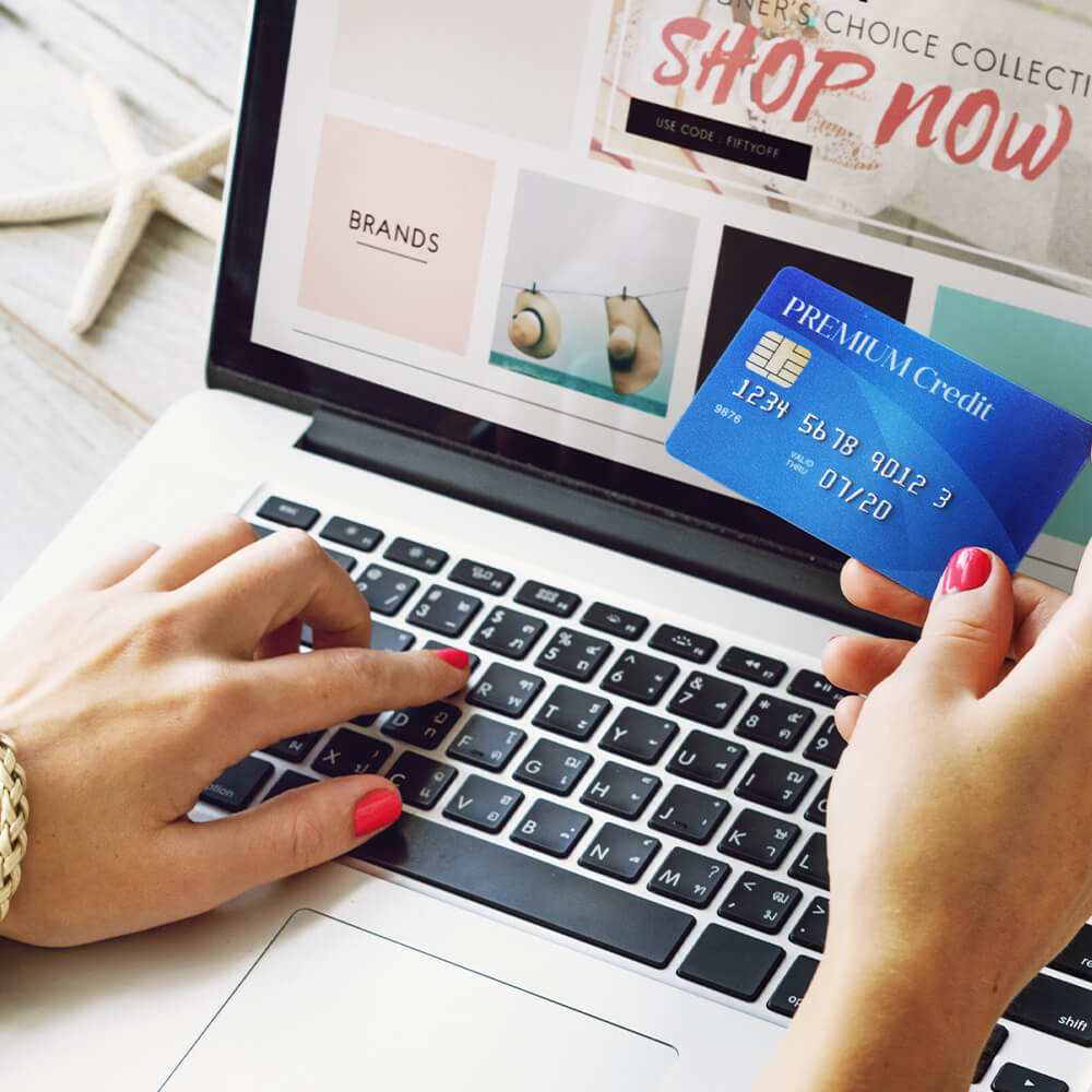 Person holding a credit card in front of a laptop