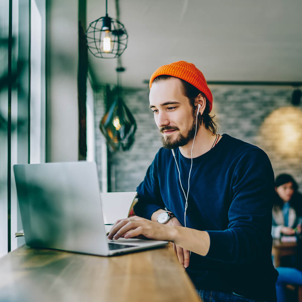Man with headphones working on a laptop in a coffee shop