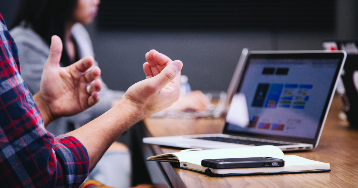 Man gesticulating with hands in front of a laptop
