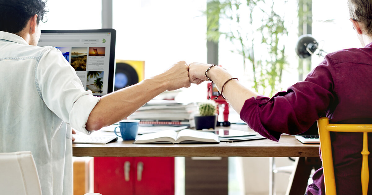 People sitting at a desk, fist bumping