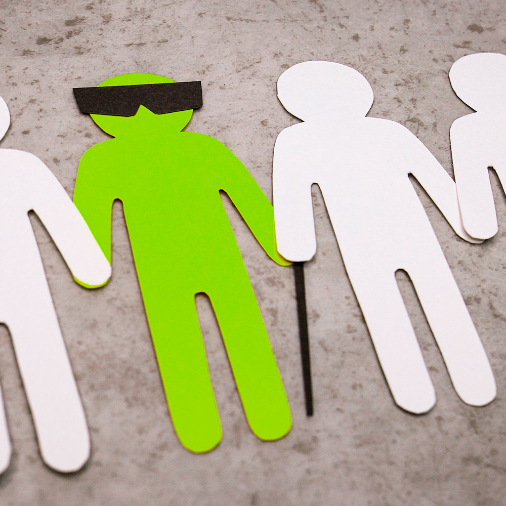 Cut-out paper illustrations depicting a group of people holding hands and assisting a visually impaired or blind person.
