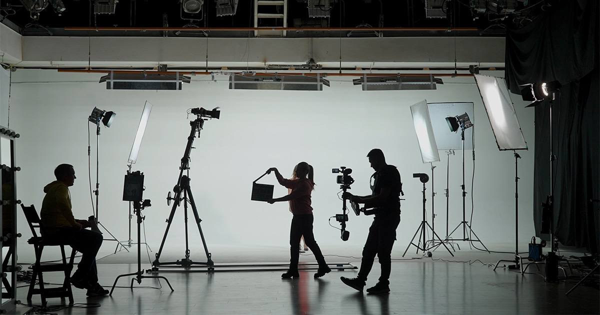 A filming crew on the dark set with light-up background